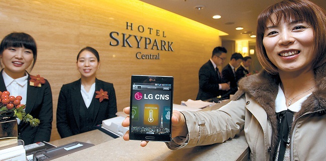 A Japanese tourist receives a smartphone after checking in at the lobby of the Skypark Central Hotel in Myeong-dong, Seoul, Tuesday. (LG CNS)