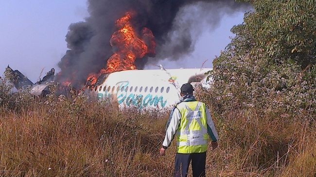 A man walks to the fuselage of an Air Bagan passenger plane burning after it crashed near Heho airport in Myanmar’s eastern Shan state on Tuesday.   AFP-Yonhap News
