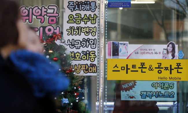 A sign on the window of a mobile phone sales outlet in downtown Seoul advertises free phones on Monday.   Yonhap News