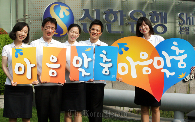 Shinhan Bank employees pose while promoting the bank’s new customized service in May in front of the bank headquarters in Seoul.   Shinhan Bank