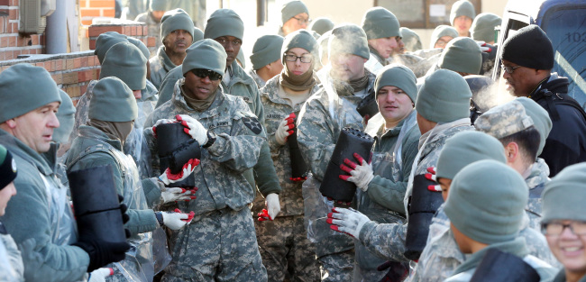 Soldiers of the U.S. 2nd Infantry Division in Dongducheon, Gyeonggi Province, relay briquettes to homes in a nearby village on Wednesday. About 70 soldiers raised 5 million won to give 10,000 briquettes to residents who can barely afford to buy fuel.   Yonhap News