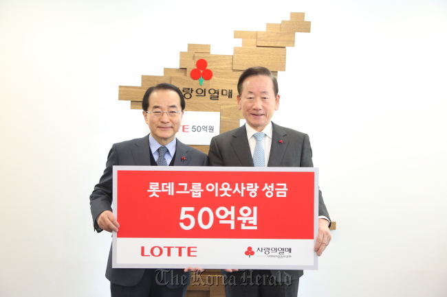 Lee In-won (left), vice chairman of Lotte Group policy headquarters, poses for a photo with Lee Dong-kurn, chairman of the Community Chest of Korea, after donating 5 billion won to the charitable fund-raiser in Seoul on Wednesday.   Community Chest of Korea