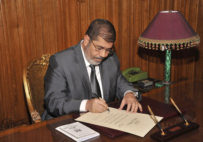 <YONHAP PHOTO-0009> In this image released by the Egyptian Presidency and taken late Tuesday, Dec. 25, 2012, President Mohammed Morsi signs into law the country's Islamist-backed constitution. Egypt's government asked parliament Wednesday to prioritize legislation to organize parliamentary elections, regulate the media and fight corruption as the upper chamber held its first session with temporary new powers granted by the constitution.(AP Photo/Egyptian Presidency)/2012-12-27 00:17:20/ <저작권자 ⓒ 1980-2012 ㈜연합뉴스. 무단 전재 재배포 금지.>
Egypt’s President Mohammed Morsi signs into law the country’s Islamist-backed constitution.   AP-Yonhap News
