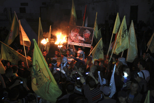 Palestinians hold torches and posters of late Palestinian President Yasser Arafat and late Hamas founder and spiritual leader Sheik Ahmed Yassin, during a rally marking the 48th anniversary of the Fatah movement in Gaza City on Monday.   AP-Yonhap News