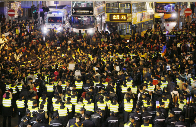 Anti-government protesters, surrounded by police officers, block the main road in Hong Kong on Tuesday to call for the resignation of Hong Kong Chief Executive Leung Chun-ying.   AP-Yonhap News