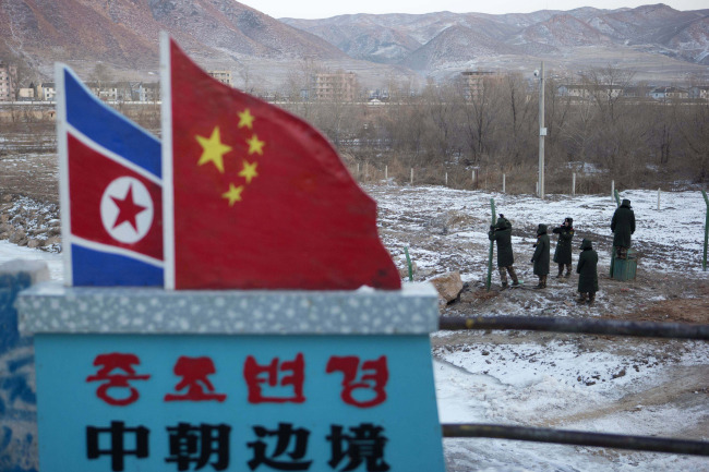 Chinese paramilitary policemen build a fence near a concrete marker depicting the North Korean and Chinese national flags with the words “China-North Korea Border” at a crossing in the Chinese border town of Tumen in eastern China’s Jilin Province on Dec. 8.   AP-Yonhap News