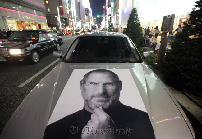 A car bearing a photograph of Steve Jobs is parked outside the Apple store in the Ginza district of Tokyo.   Bloomberg