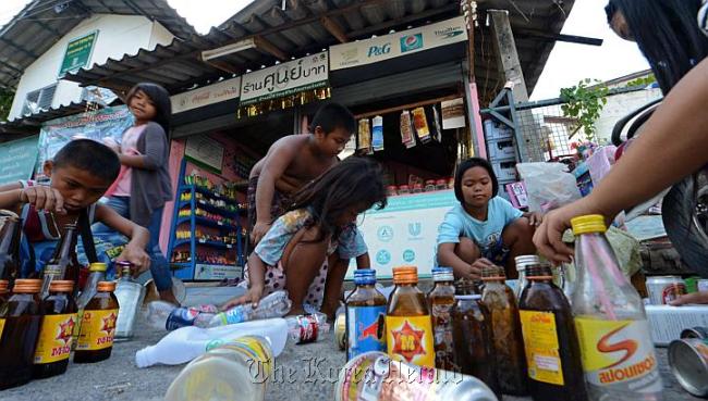 Thai children select used bottles and cans before trading them at a “zero baht shop” in Bangkok.   AFP-Yonhap News