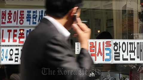 A man walks past a mobile phone shop in Seoul.   Yonhap News