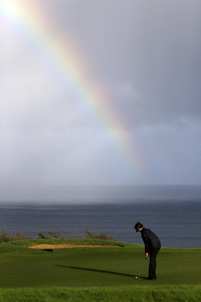 Bubba Watson putts in view of a rainbow behind on the 13th hole during the first round at the Tournament of Champions PGA golf tournament in Kapalua on Monday.   AP-Yonhap News