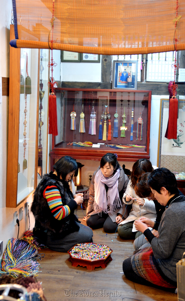 Students learn to tie traditional Korean maedeup knots during a hands-on class at the Donglim Knot Workshop in Bukchon Hanok Village, Seoul