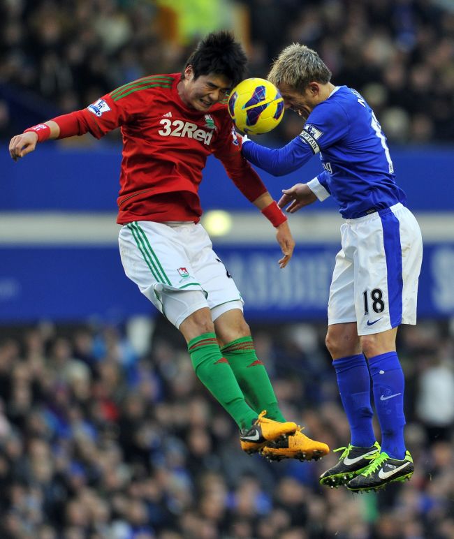 Swansea City’s Ki Sung-yueng (left) and Everton’s Phil Neville challenge for the ball on Saturday.   AFP-Yonhap News