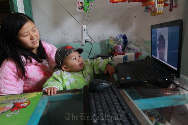 Olsen sits with his aunt in front of the computer. At 11 a.m. every day, he video chats with his parents in the U.S.   China Daily