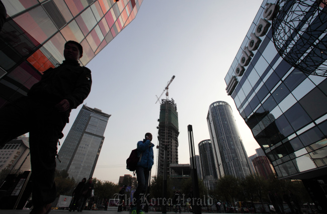 Pedestrians walk past commercial buildings in the Sanlitun area of Beijing.   Bloomberg