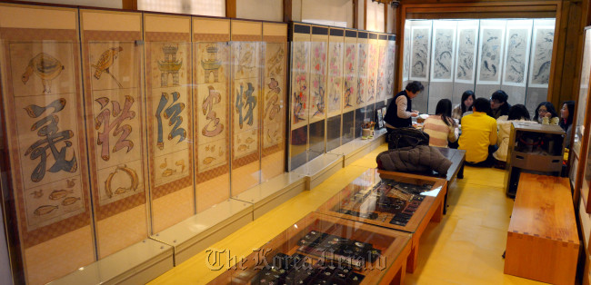 Visitors join in a folk painting class offered by the Gahoe Minhwa Museum.   Lee Sang-sub/The Korea Herald