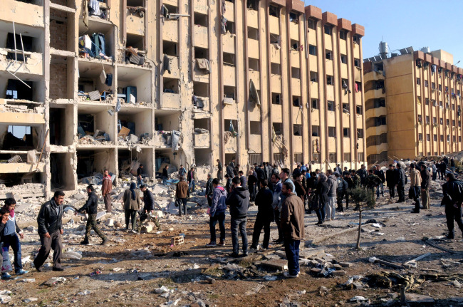 Syrian people gather at the site after an explosion hit a university in Aleppo, Syria, Tuesday.   AP-Yonhap News