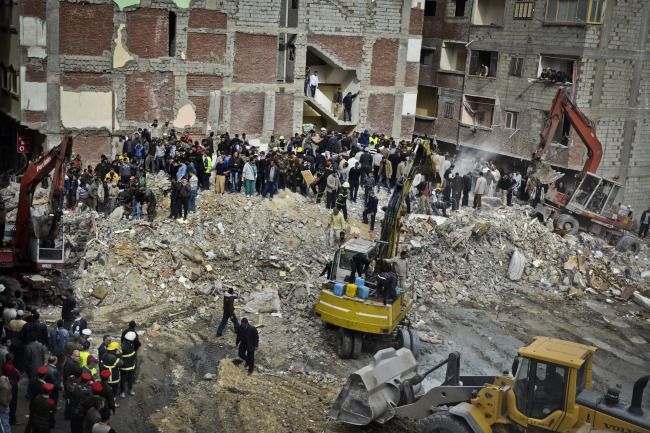 Egyptians stand in rubble after an eight-story building collapsed in Alexandria, Egypt, Wednesday.   AP-Yonhap News