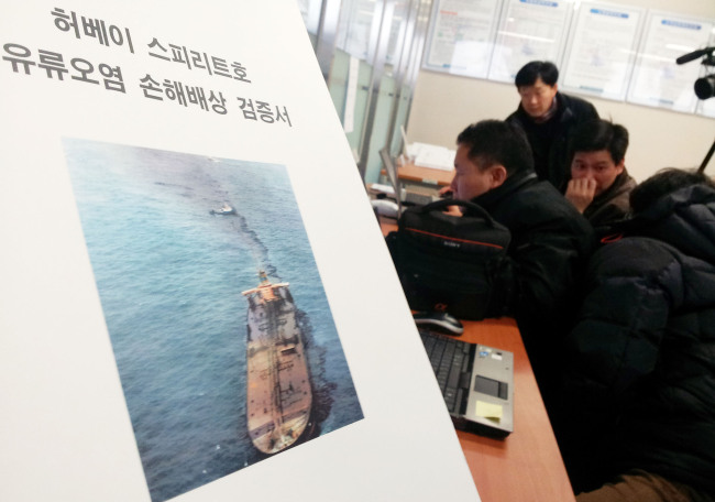 Taean residents read the court ruling that awarded compensation for an oil spill to victims in the region on Wednesday at a branch office of Daejeon District Court in Seosan, South Chungcheong Province.   Yonhap News