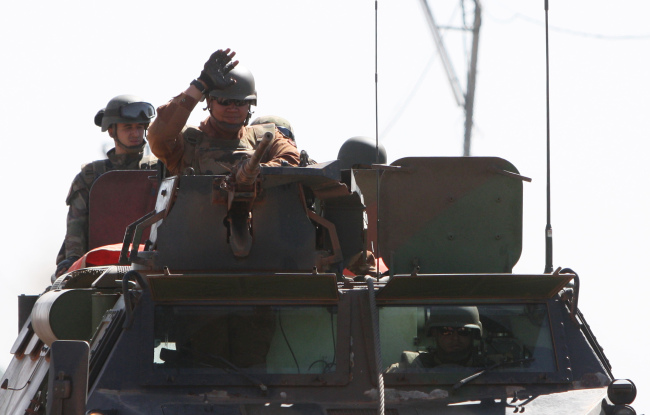 French soldiers wave as they drive near Markala, approximately 40 kilometers from Segou, in central Mali, Thursday.   AP-Yonhap News