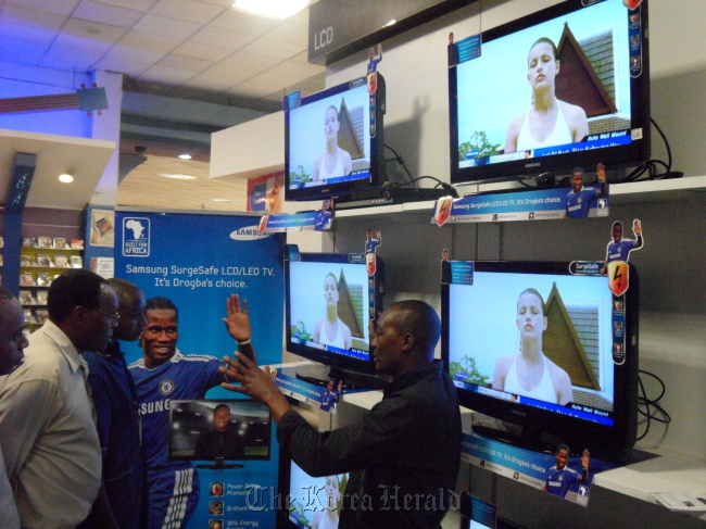 A Samsung Electronics’ product salesman explains the functions of the firm’s “Surge Safe TV” to customers at a store in Africa in September 2011.
Samsung Electronics