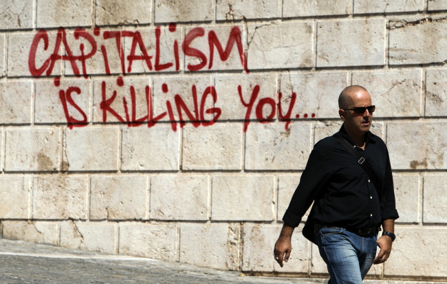 A pedestrian walks in front of graffiti in Athens.    AP-Yonhap News