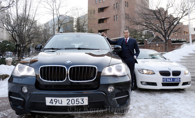 Ernesto Torres-Pereyera stands between the BMW X5 and his own BMW 328i convertible in the Jeong-dong area, central Seoul.   Ahn Hoon/The Korea Herald