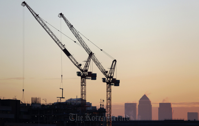 The Canary Wharf financial and business district stands on the horizon beyond construction cranes in the City district in London.    Bloomberg