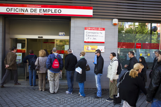 Jobseekers wait to enter an employment center after opening in Madrid.   Bloomberg