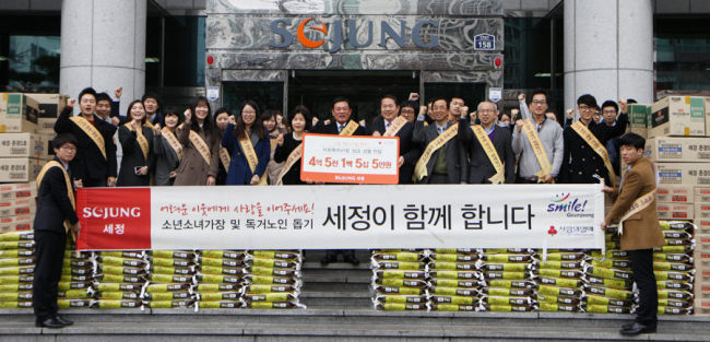 Sejung Group, a Busan-based fashion business, launches its service corps in front of its headquarters in Busan on Tuesday. They gave rice, noodles and household goods to 100 seniors who live alone.   Yonhap News
