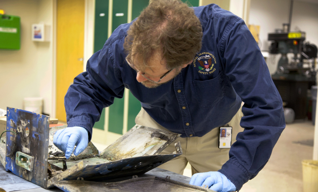 NTSB Materials Engineer examines the casing from the battery involved in the Japan Airlines Boeing 787 fire in a plane that had already landed in Boston at NTSB headquarters in Washington on Wednesday.   AP-Yonhap News