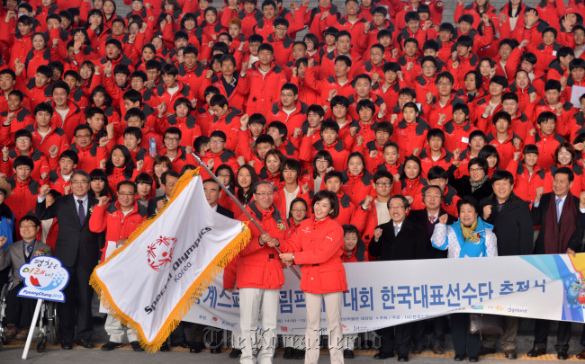 Na Kyung-won (right), chairwoman of the 2013 Special Olympics World Winter Games Organizing Committee, and Kim Yong-jik, chief of the South Korean team, wave the Special Olympics flag during the team launching ceremony in Seoul on Thursday.   Lee Sang-sub/The Korea Herald