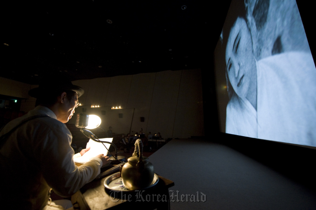 Actor Cho Hee-bong (left), the narrator of Korea’s oldest extant silent film “Crossroads of Youth” (1934), performs along to the silent movie accompanied by live music.   Korean Film Archive