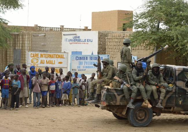 People watch Malian troops as they enter the historic city of Timbuktu, occupied for 10 months by Islamists who imposed a harsh form of sharia, Monday.   AFP-Yonhap News