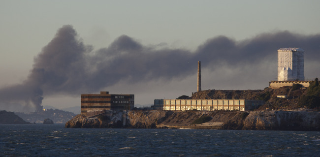 In this Aug. 6, 2012 file photo, smoke pours from a fire at the Chevron Richmond Refinery, seen behind Alcatraz Island in San Francisco.   AP-Yonhap News