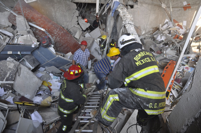 Firefighters belonging to the Tacubaya sector and workers dig for survivors after an explosion at a building adjacent to the executive tower of Mexico’s state-owned oil company PEMEX in Mexico City on Thursday.   AP-Yonhap News