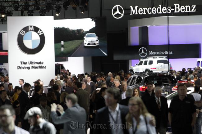 Attendees walk through the Bayerische Motoren Werke AG (left) and Daimler AG Mercedes-Benz stands during the Auto Show in Los Angeles, California, in November.   Bloomberg