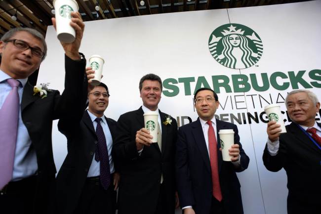 Starbucks president for China and the Asia-Pacific John Culver (left) stands with guests during the opening ceremony of the first Starbucks store in Ho Chi Minh City on Friday.    AFP-Yonhap News