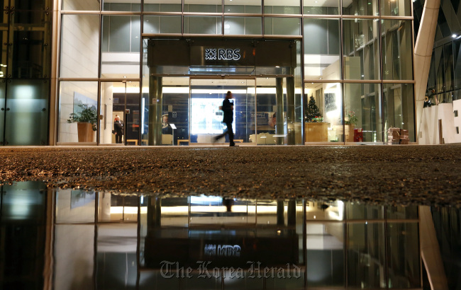 A pedestrian passes the entrance to the regional offices of the Royal Bank of Scotland Group Plc in Manchester, England.   Bloomberg
