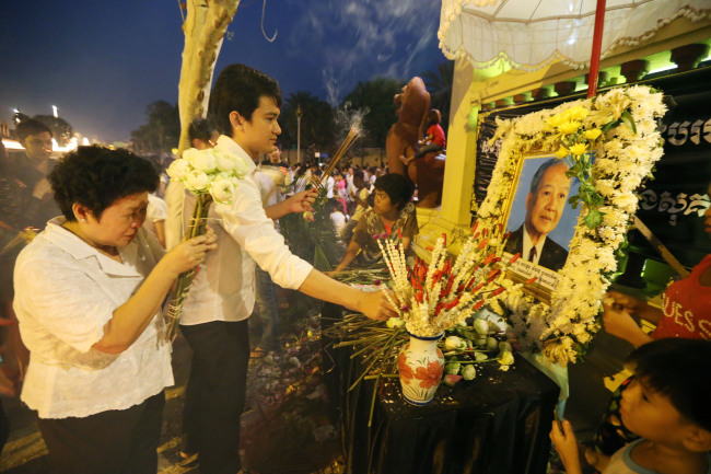 People pray to pay their respects to the late former King Norodom Sihanouk in front of the Royal Palace in Phnom Penh on Sunday.   Xinhua-Yonhap News