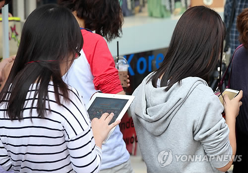 People playing mobile games using their smartphones and tablet computers. (Yonhap News)