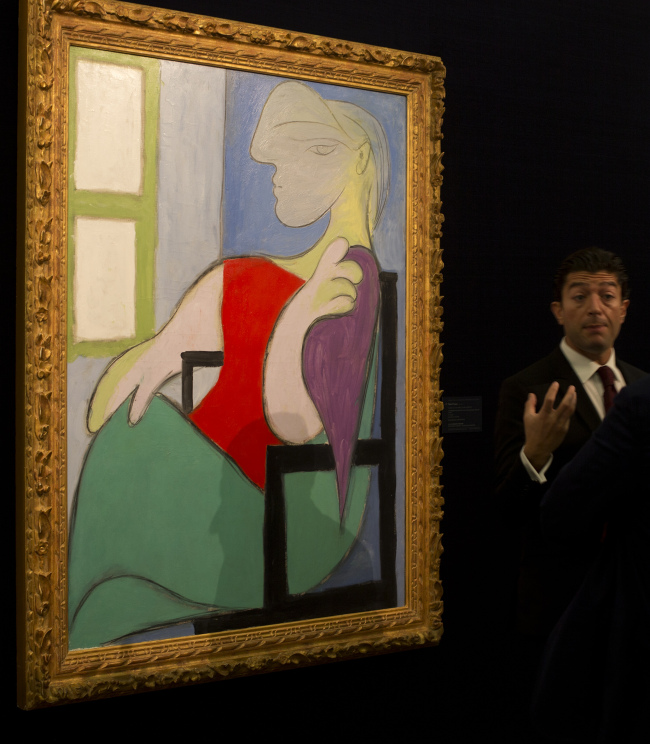 An expert from Sotheby’s auction house gestures as he describes a 1932 painting by Pablo Picasso entitled “Femme Assise Pres d’une Fenetre (Woman Sitting Near a Window),” at Sotheby’s auction house during a press preview in London on Jan. 31.  AP-Yonhap News