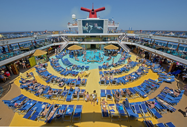 In this June 23, 2012 photo provided by Carnival Cruise Lines, vacationers aboard the Carnival Breeze enjoy sunbathing at sea while watching a movie at the Carnival’s Seaside Theatre.    AP-Yonhap News