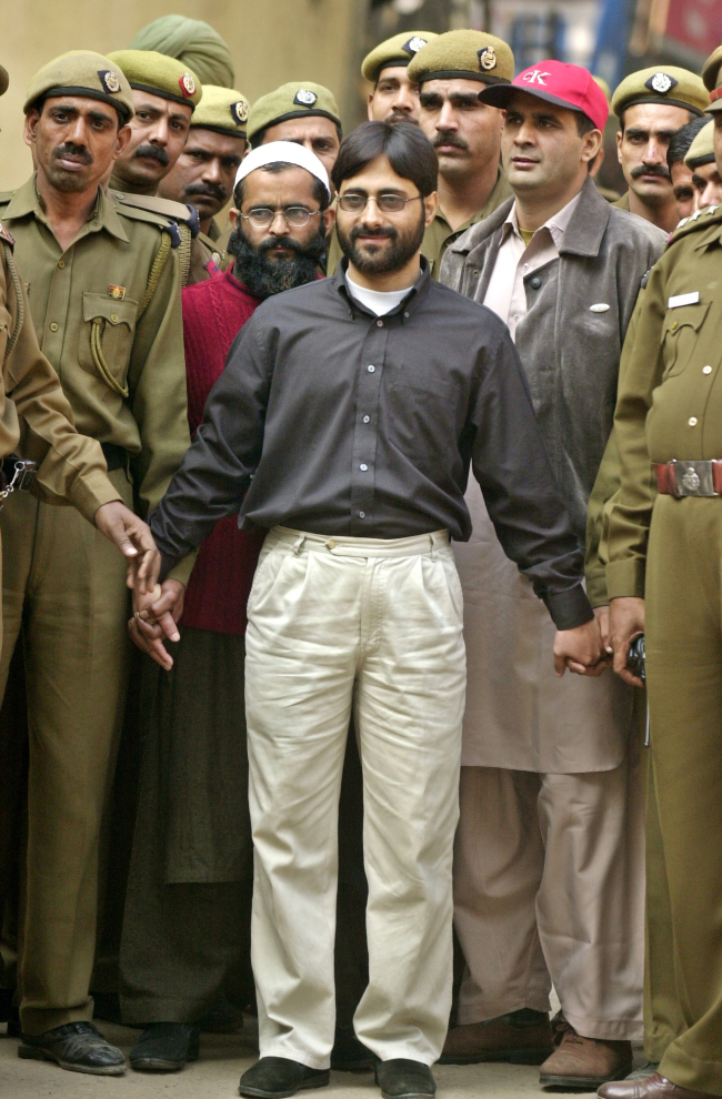 In this Dec. 18, 2002 file photo, Mohammed Afzal Guru, center left wearing red, Syed Abdul Rahman Geelani, center, and Shaukat Hussain Guru, center right, are brought out of court after being sentenced to death for aiding the 2001 attack on the Indian Parliament, in New Delhi, India. Afzal has been hanged in an Indian prison, a senior Indian Home Ministry official said Saturday. Government prosecutors had said Guru was a member of the militant group Jaish-e-Mohammed, a charge he denied.