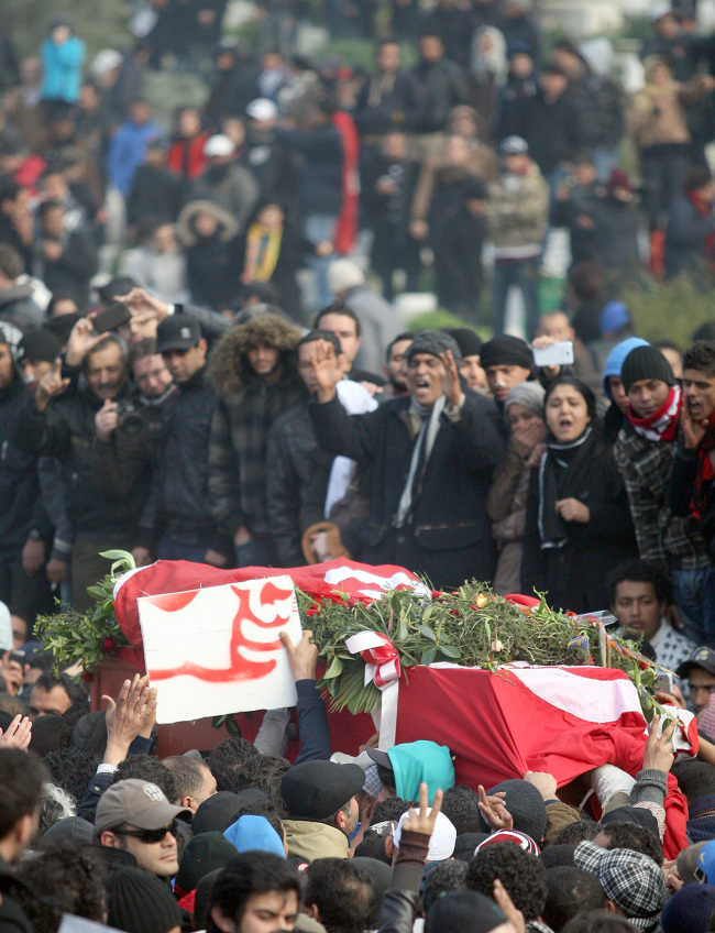The coffin, wrapped in the Tunisian red flag, of slain opposition leader Chokri Belaid is carried at el Jallez cemetery while thousands attend his funeral near Tunis, Friday.   AP-Yonhap News