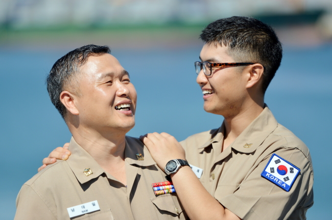 Warrant Officer Nam Dae-il (left), 52, joins his son Petty Officer 2nd Class Nam Hyun-jae, 22, aboard Munmu the Great, a Korean-made 4,400-ton destroyer of the anti-piracy Cheonghae Unit off Somalia on Sunday.   Joint Chiefs of Staff