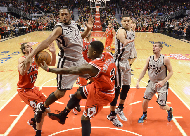 Chicago Bulls point guard Nate Robinson (center) passes the ball to center Joakim Noah (left) as San Antonio Spurs center Boris Diaw (second from left) defends during the first half at the United Center in Chicago on Monday.   UPI-Yonhap News