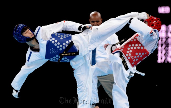 Lee Dae-hoon (left) of South Korea kicks high against an Egyptian opponent in the 2012 London Olympic taekwondo quarterfinals in August, last year.    Joint Photo Press Corps