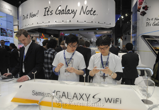 Visitors inspect Samsung Electronics Co. Galaxy S smartphones on display at the Mobile World Congress in Barcelona, Spain, February 2012.   Bloomberg