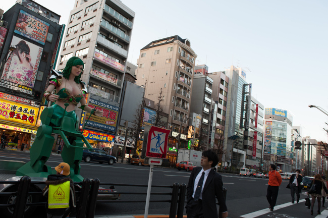 A pedestrian looks at a promotional statue displayed by the side of a road in the district of Akihabara in Tokyo.   Bloomberg