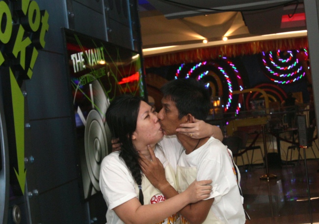 kkachai Tiranarat, center, and Laksana Tiranarat walk to the restroom during the World's Longest Continuous Kiss Competition in Pattaya, southeastern Thailand, Thursday. (AP-Yonhap News)